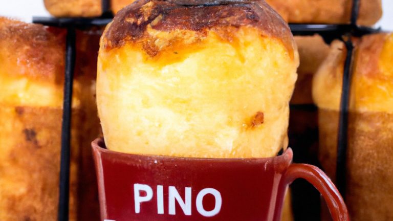 Imagem de um panetone de caneca na Airfryer. O panetone é marrom dourado e tem uma textura fofa, com uma cobertura de açúcar de confeiteiro polvilhada por cima. A caneca é branca e tem uma alça vermelha. Ao fundo, há uma Airfryer preta.