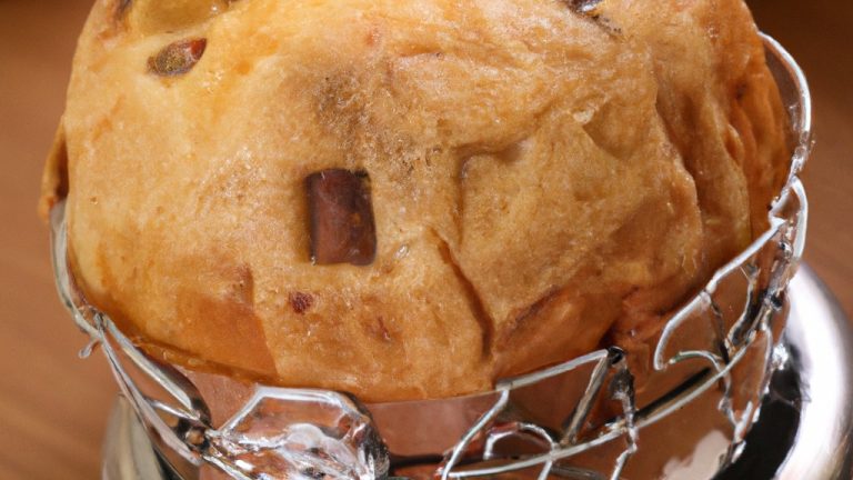 Imagem de um panetone salgado dourado e crocante assado em uma Airfryer, com queijo derretido escorrendo pelas laterais. O panetone é guarnecido com ervas frescas e fatias de tomate para um toque extra de sabor.