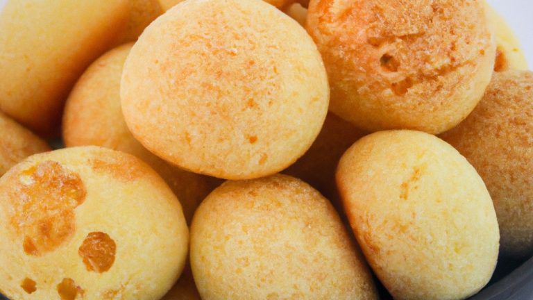 Imagem de pão de queijo cottage feito na airfryer. Os pães de queijo são redondos, dourados e crocantes por fora, com um interior macio e aerado. Eles são apresentados em um prato branco, polvilhados com salsa picada.