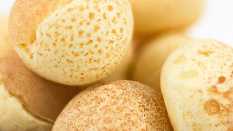 Foto de pães de queijo dourados e crocantes cozidos em uma airfryer, dispostos em um prato branco. Os pães de queijo têm um interior macio e aerado, e o exterior é crocante e dourado.