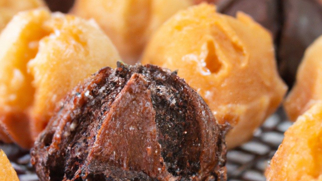 Imagem de um petit gateau de chocolate feito na Airfryer. O bolo é pequeno e redondo, com uma cobertura de chocolate derretido. O interior do bolo é úmido e cremoso, com um centro derretido. O bolo é servido em um prato branco com uma colher ao lado.