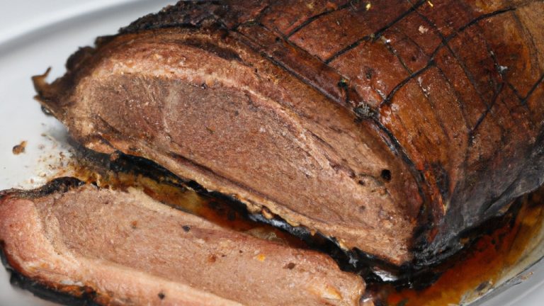 Imagem de uma picanha suína assada na Airfryer. A carne está dourada e suculenta, e é servida com uma salada de folhas verdes e um molho à parte.