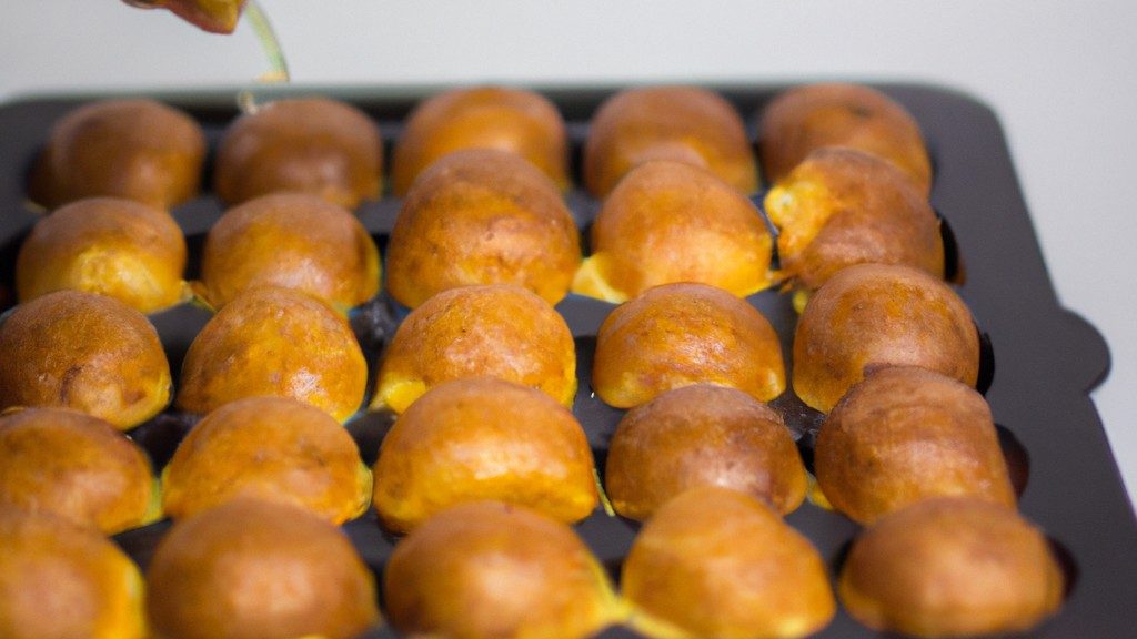 Imagem de uma queijadinha frita na Airfryer, com uma casca dourada e crocante e um recheio cremoso e macio. A queijadinha está em um prato azul, com uma colher ao lado.