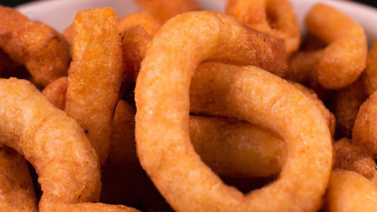 Imagem de uma porção de rabanada salgada crocante cozida em uma Airfryer. As rabanadas são douradas e cobertas com uma mistura de queijo parmesão e ervas, e são servidas com um molho de tomate à parte.