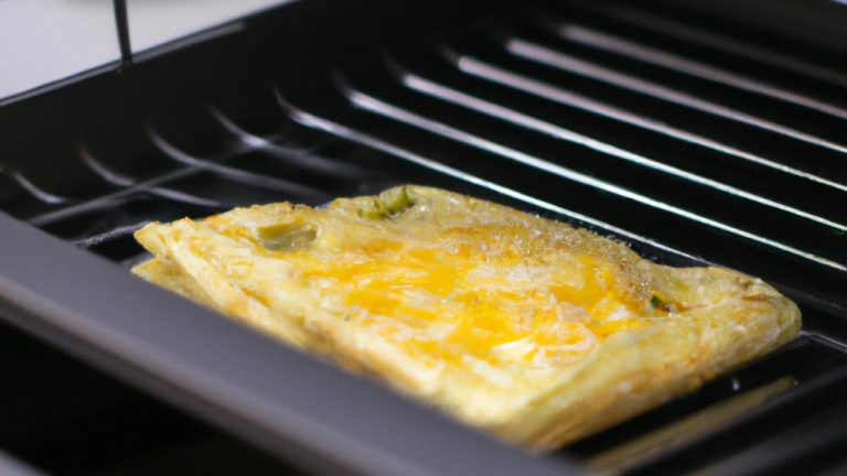 Imagem de um omelete cozido na Airfryer. O omelete é marrom dourado e tem uma textura fofa. Está coberto com queijo derretido e cebolinha picada.