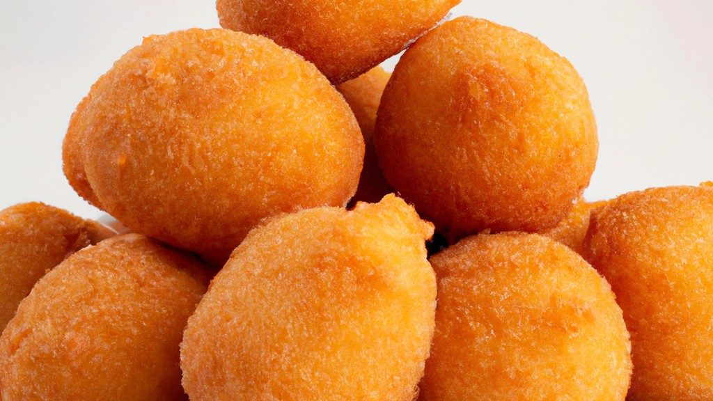 Imagem de uma fritadeira de ar com quatro andares, cada andar com uma cesta de metal perfurada. A fritadeira é branca com detalhes em preto e tem um visor digital e botões de controle.