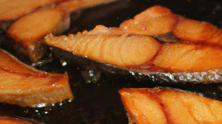 Uma fotografia de cima para baixo de um salmão grelhado na fritadeira sem óleo, servido em um prato branco com fatias de limão ao lado. O salmão tem uma crosta dourada e escamosa, e o interior é macio e suculento. A imagem mostra o contraste entre a crosta crocante e o interior úmido do salmão.